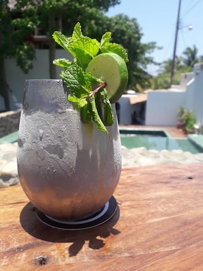 A glass of iced beverage with mint leaves and a lime slice on a wooden surface.