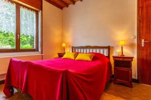 Una stanza con un letto, due comodini, una finestra e una porta.