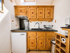 A compact kitchen with wooden cabinets, a dishwasher, and a sink. - Charming slope-side apartment with pool (Flumet)