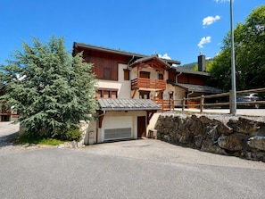 A two-story building with a stone wall and a garage door.