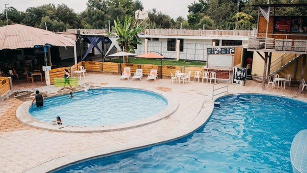 Zona de piscina con piscina circular, sillas de descanso y un área de estar techada.