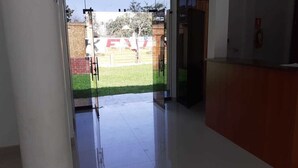 Un área de recepción con un puerta de vidrio que da al exterior, un mostrador de recepción y un extintor en la pared.