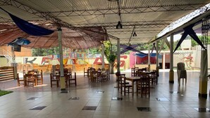 Un comedor interior con suelo de baldosas, mesas y sillas de madera.