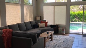 A living room with a sectional sofa, a coffee table, and a ceiling fan. - Perfect Escape - Festival close, on golf course, private salt water pool, +++! (Indio)