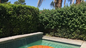 A clear swimming pool with a floating orange and yellow sun float, surrounded by a tiled edge and lush green hedges. - Perfect Escape - Festival close, on golf course, private salt water pool, +++! (Indio)