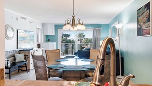 A modern kitchen with a round dining table, a built-in oven, and a large window overlooking a balcony.