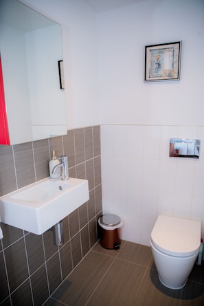 Um banheiro moderno com pia branca, vaso sanitário e lixeira.