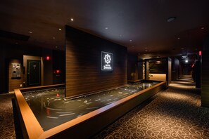 Un hall d’hôtel comprenant un comptoir d’accueil, un panneau d’affichage numérique et un élément décoratif aquatique.