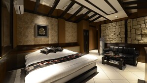 Une chambre moderne avec un grand lit, un mur en pierre, un canapé en cuir et une cheminée.