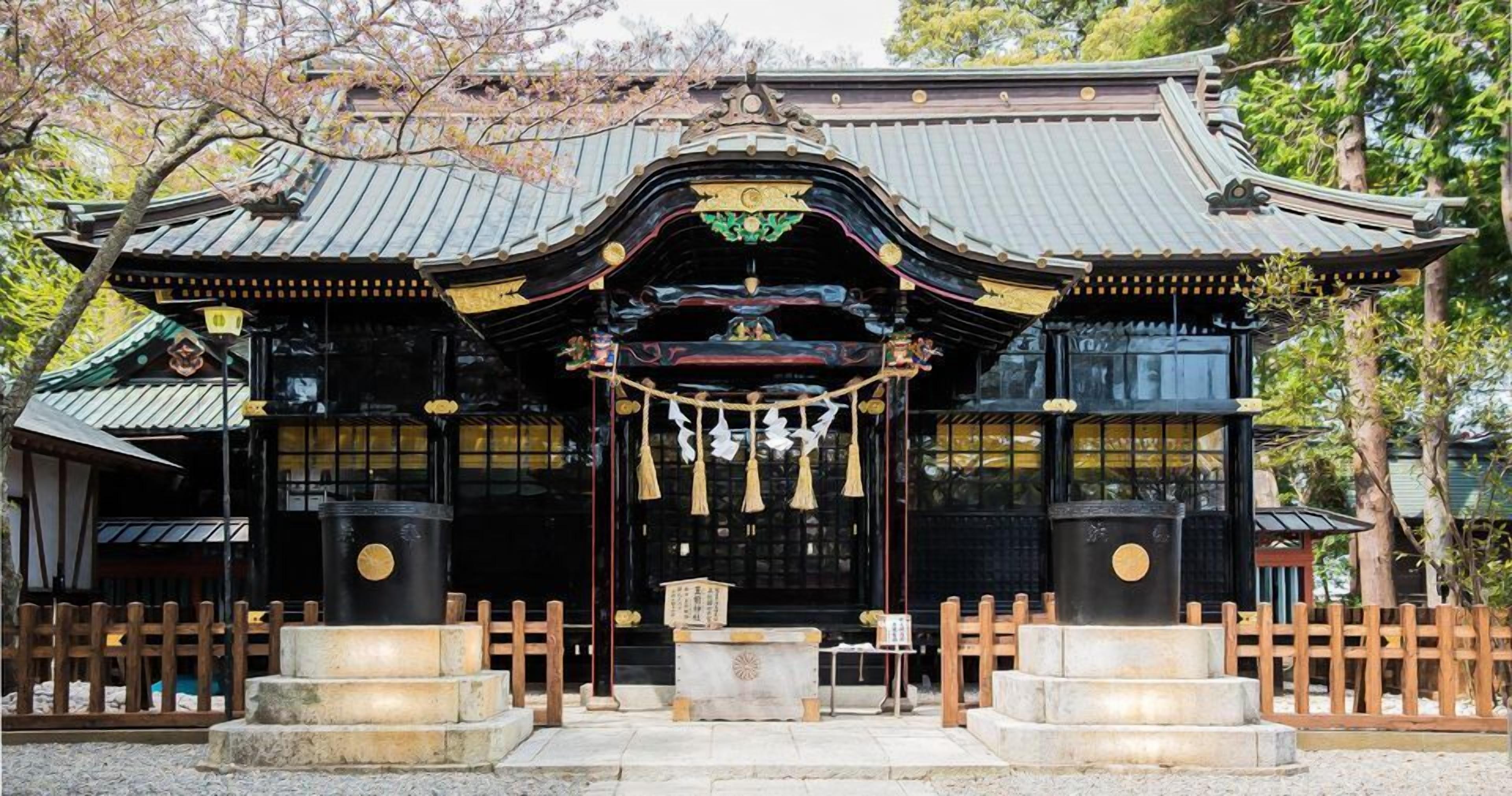 Un templo japonés tradicional con tejado curvo, puerta torii de madera y faroles de piedra.