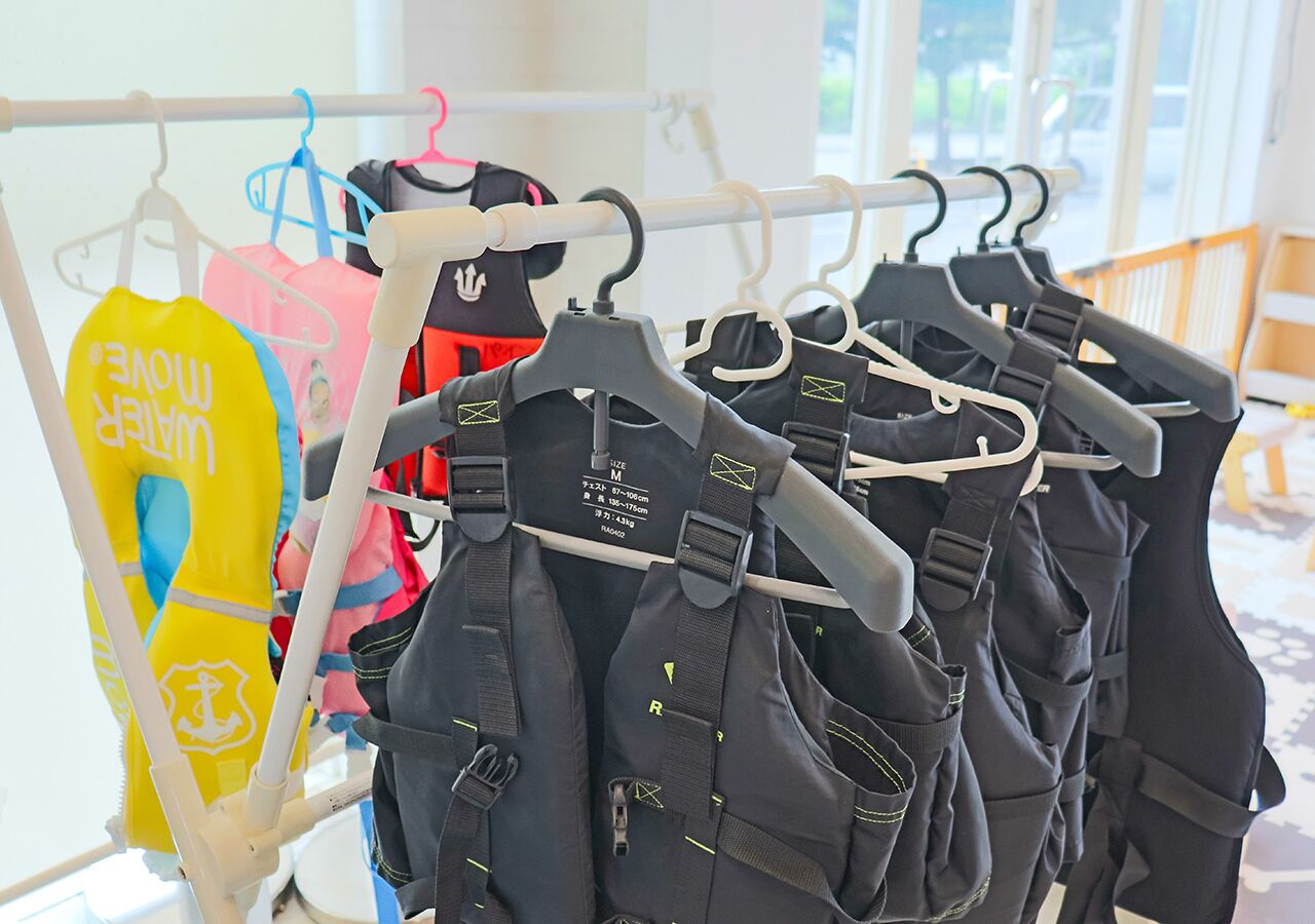 A rack of life jackets and a yellow bag with a logo.