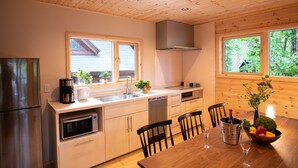 Una cocina moderna con techo de madera, electrodomésticos de acero inoxidable y una zona de comedor con una mesa y sillas de madera.