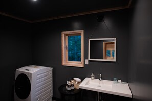 Een moderne badkamer met een grote wasmachine, een wastafel en een spiegel.