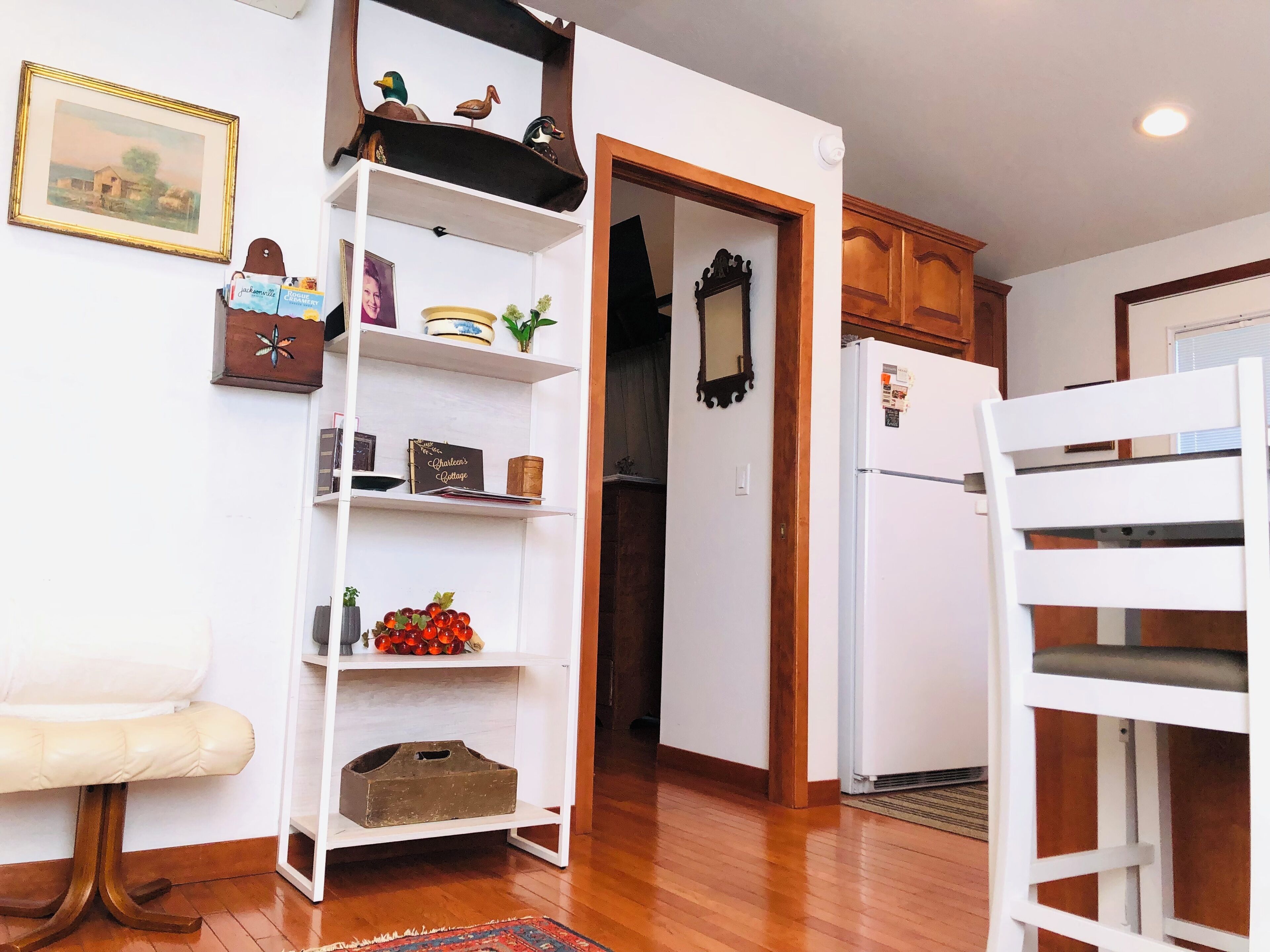 A kitchen with white cabinets, a white refrigerator, and a wooden chair.