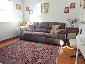 Une pièce avec un canapé marron, un tapis à motifs et des tableaux encadrés accrochés au mur.