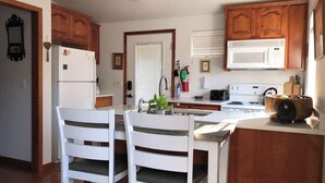 A kitchen with wooden cabinets, a white refrigerator, a stove, and a sink with a wooden bowl on the counter.