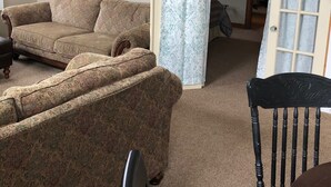Un salon avec un canapé beige, une chaise en bois et une table à manger.