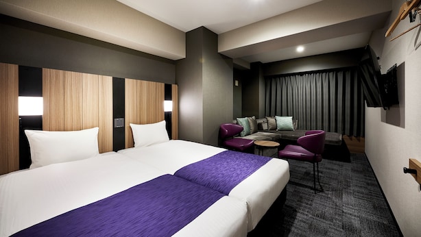 Habitación de hotel con una cama grande, un escritorio, una silla y un televisor montado en la pared.