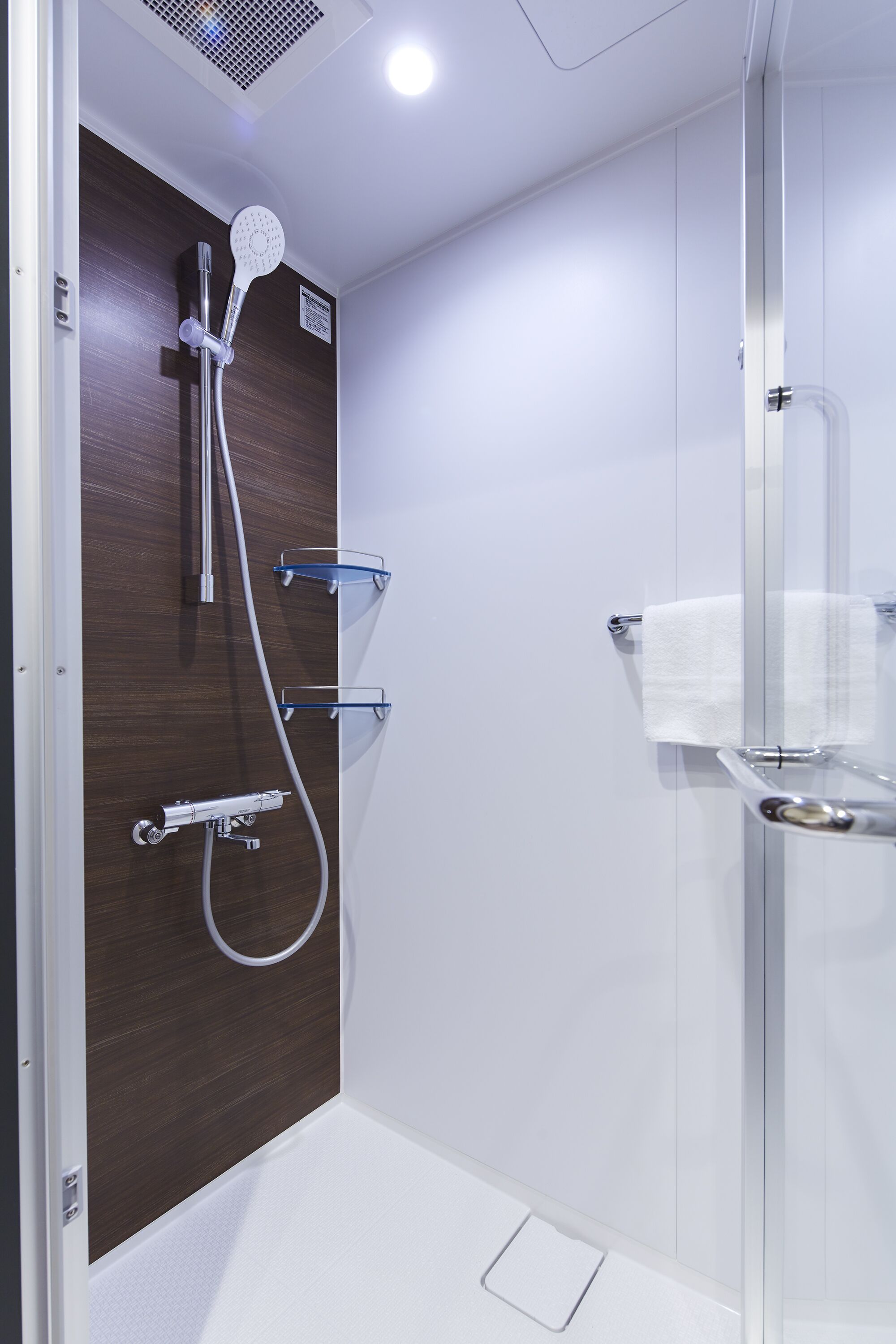 A modern bathroom with a shower, a glass enclosure, and a towel rack.