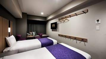 A hotel room with two beds, a seating area with a sofa and chairs, a TV, a coat rack, and a clock on the wall.