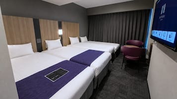 Une chambre d’hôtel avec trois lits, un téléviseur à écran plat, un bureau et une chaise.