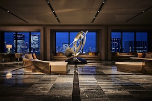 A spacious lobby with modern seating, large windows offering city views, and a distinctive sculptural centerpiece.