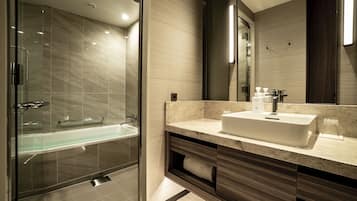 A modern bathroom with a glass-enclosed shower, a large sink, and a mirror above the vanity.