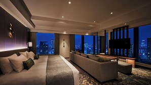 Una habitación de hotel moderna con una cama grande, un sofá, un televisor y vistas a la ciudad.