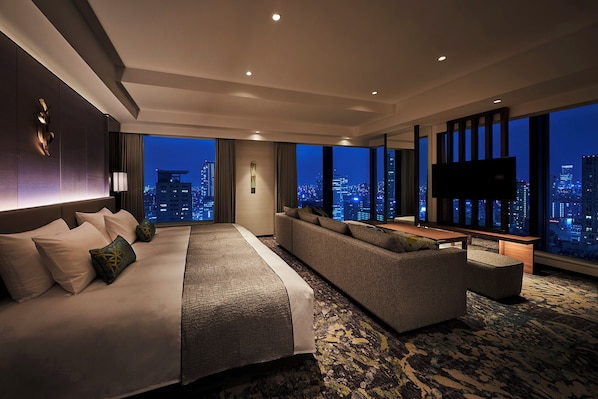 Una habitación de hotel moderna con una cama grande, un sofá, un televisor y vistas a la ciudad.
