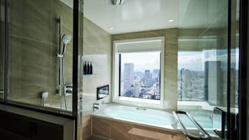 Un baño moderno con una bañera grande, un cabezal de ducha y una ventana con vistas a la ciudad.