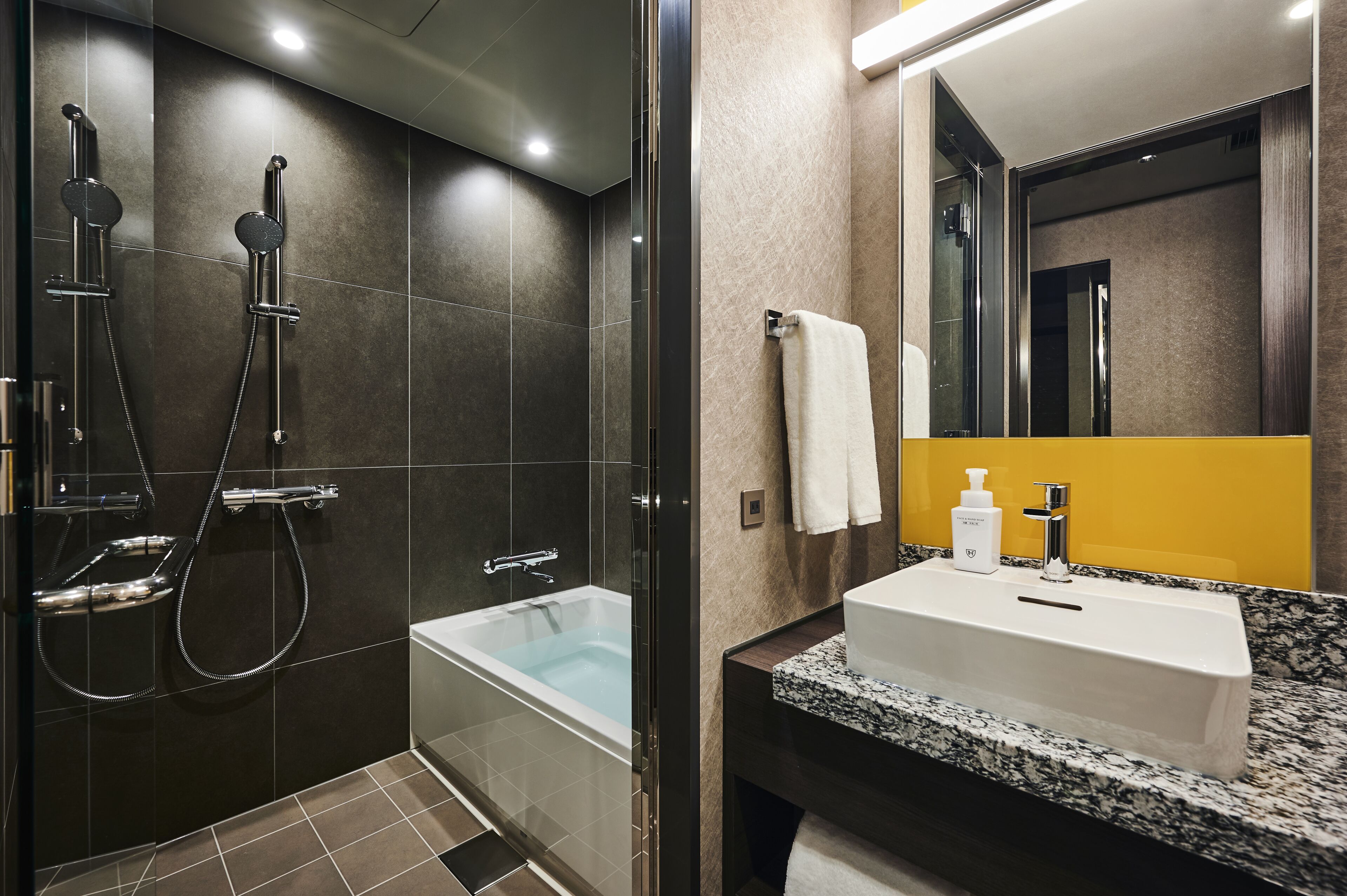 A modern bathroom with a glass-enclosed shower, a bathtub, and a sink with a marble countertop.