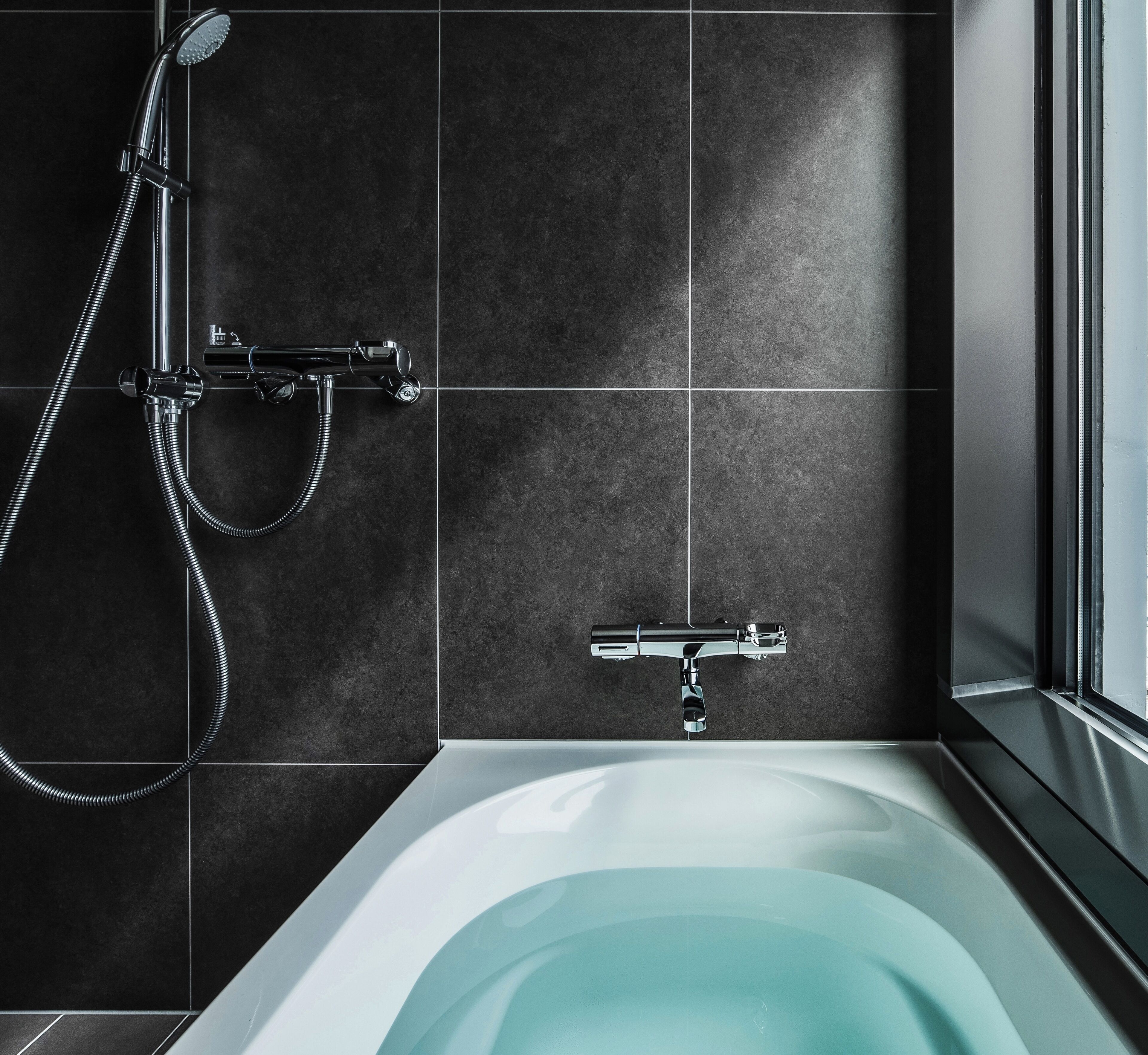 A modern bathroom with a bathtub, a shower with a handheld showerhead, and a wall-mounted faucet.