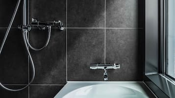 A modern bathroom with a bathtub, a shower with a handheld showerhead, and a wall-mounted faucet.