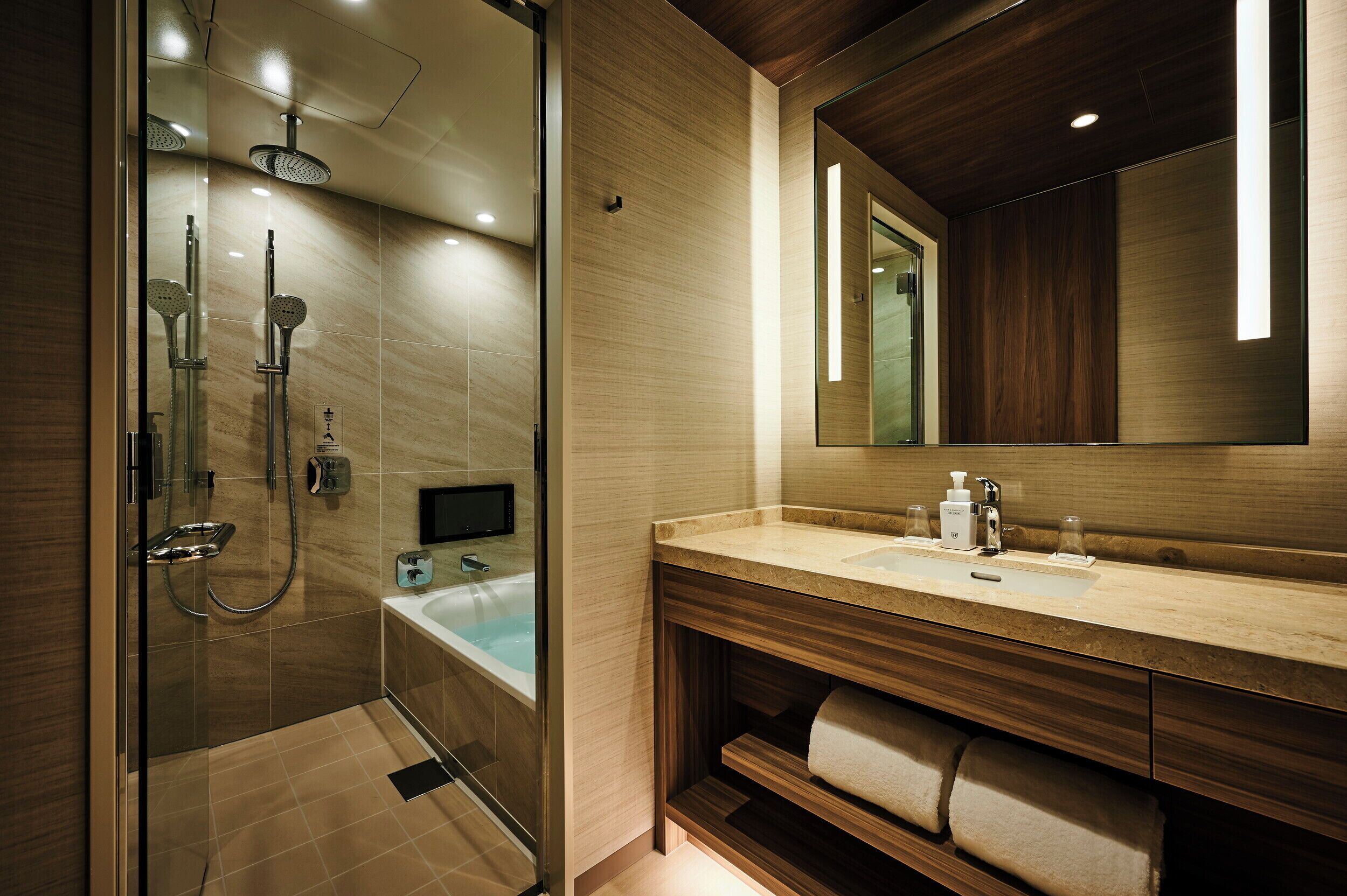 A modern bathroom with a glass-enclosed shower, a bathtub, a vanity with a mirror, and a towel rack.