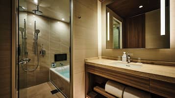 Un baño moderno con ducha de vidrio, bañera, tocador con espejo y barra para toallas.