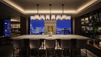 A modern kitchen with a large island, bar stools, pendant lighting, and a city view.