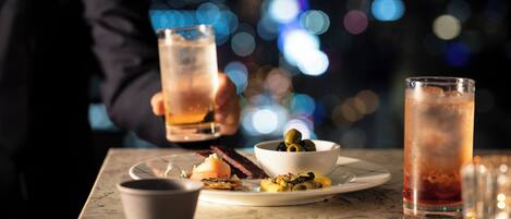 A table with a glass of iced tea, a bowl of olives, and a plate with food.