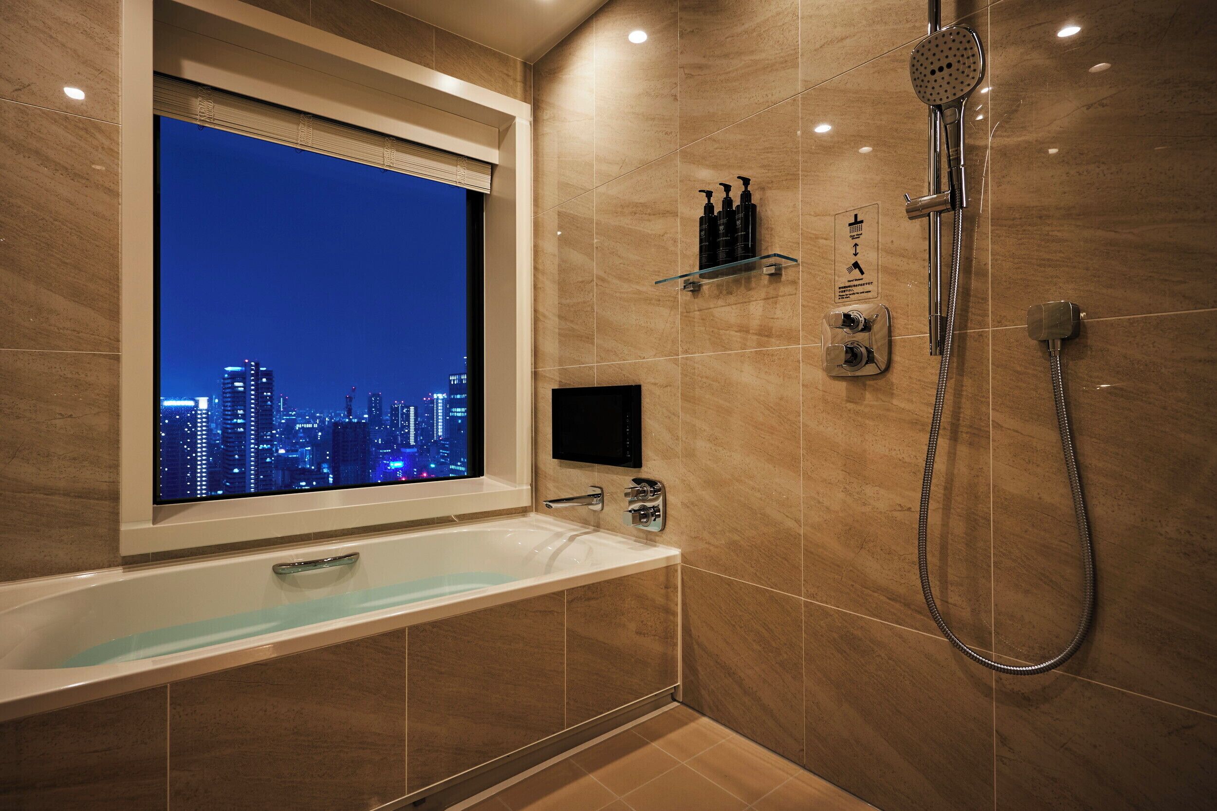 Un baño moderno con bañera, ducha y vistas a la ciudad a través de una ventana.