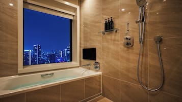 A modern bathroom with a bathtub, a shower, and a cityscape view through a window.