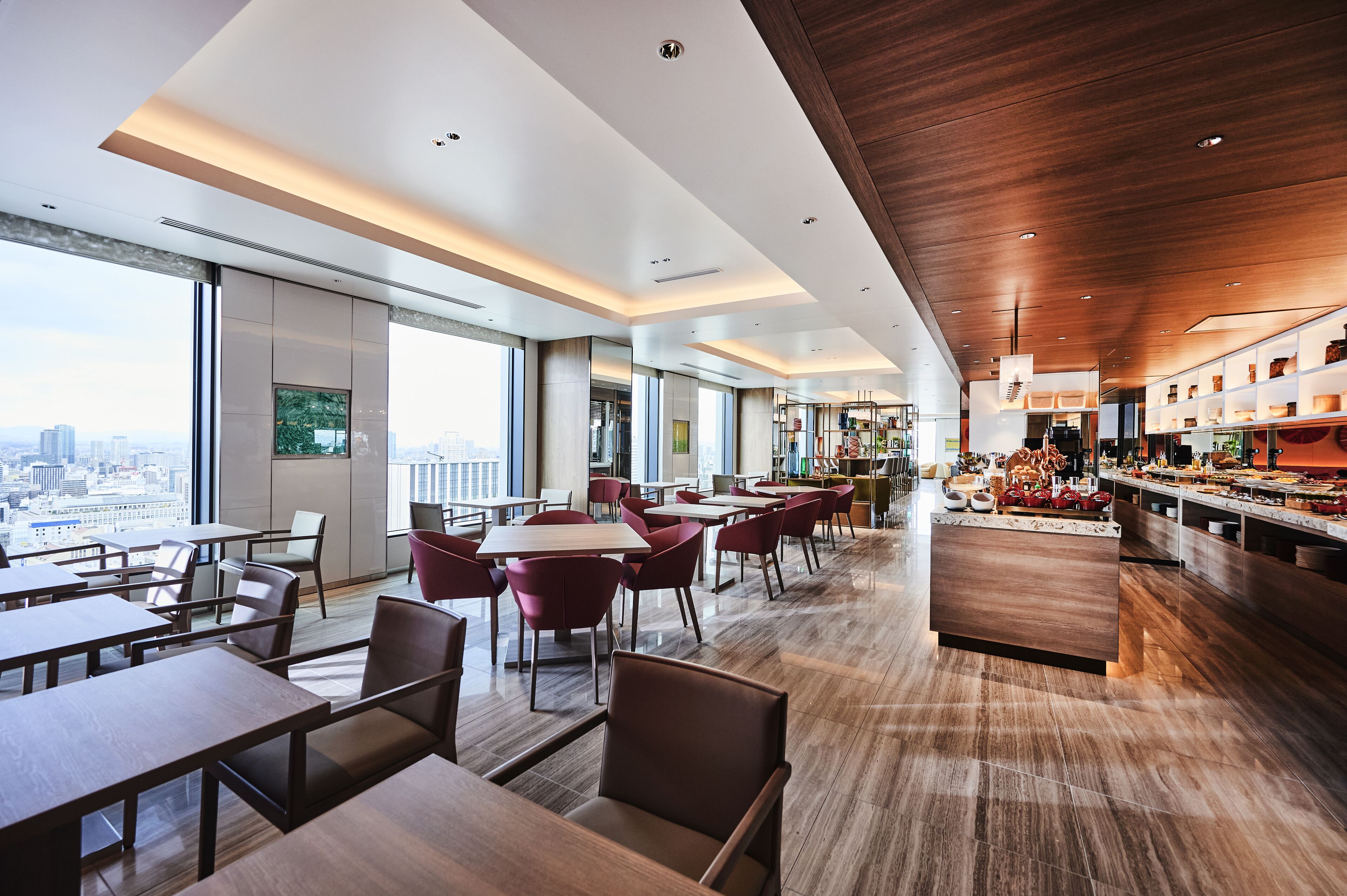 Un restaurante moderno con techos altos, amplias ventanas y vistas a la ciudad.