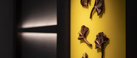 Una habitación con una pared amarilla y un suelo oscuro. Hay cuatro adornos decorativos en la pared.