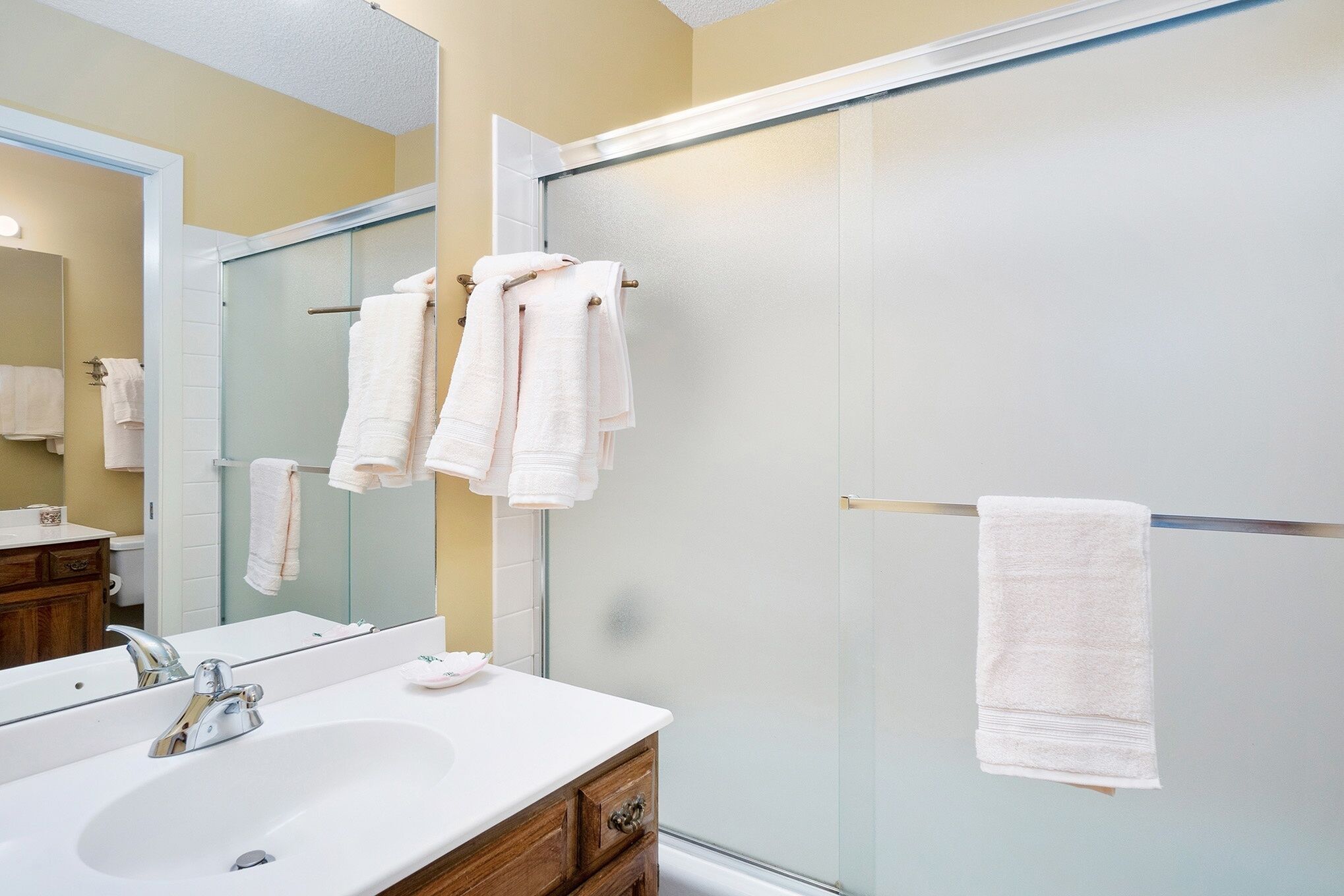 Une salle de bain équipée d’un lavabo, d’un miroir et d’une douche à parois en verre.