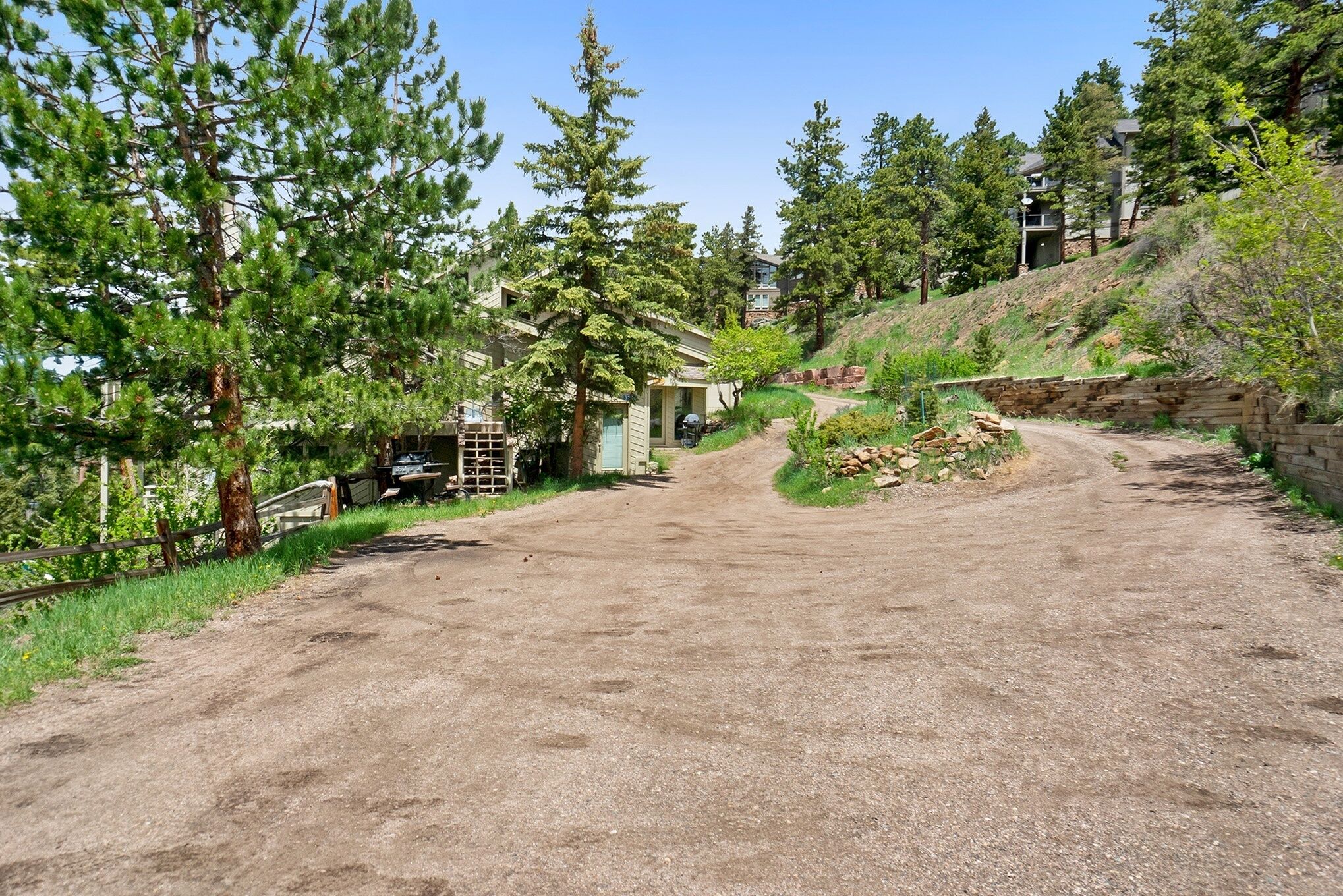 A gravel driveway leading to a house surrounded by trees.