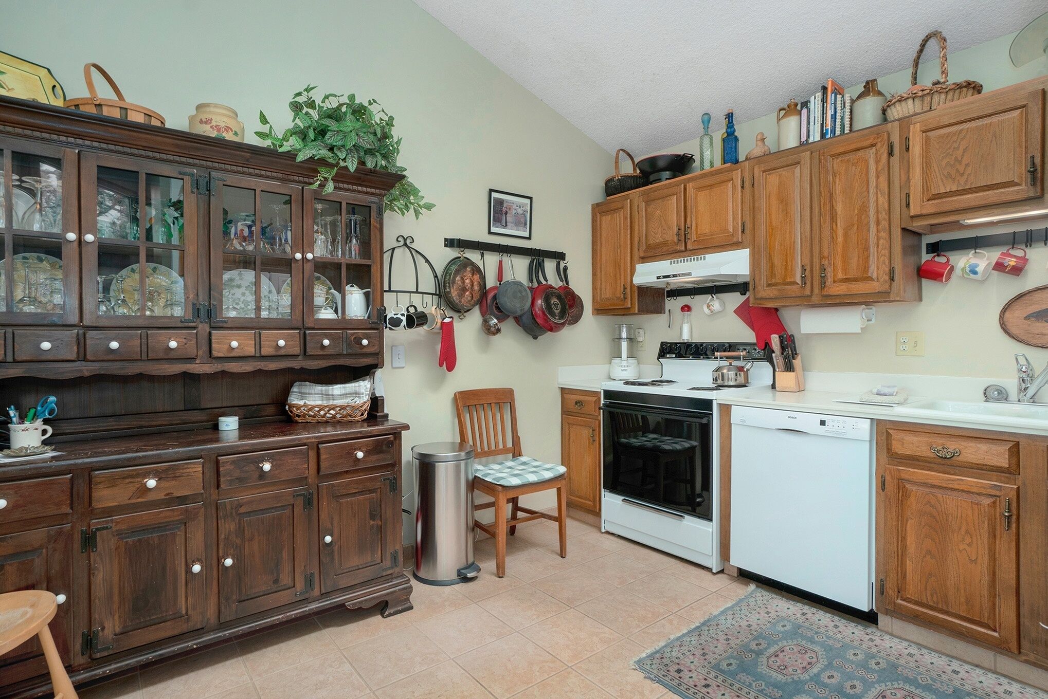 Una cucina con mobili in legno, lavastoviglie, forno e diversi utensili da cucina.