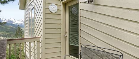 A balcony with a metal bench, a welcome sign, and a door with blinds.