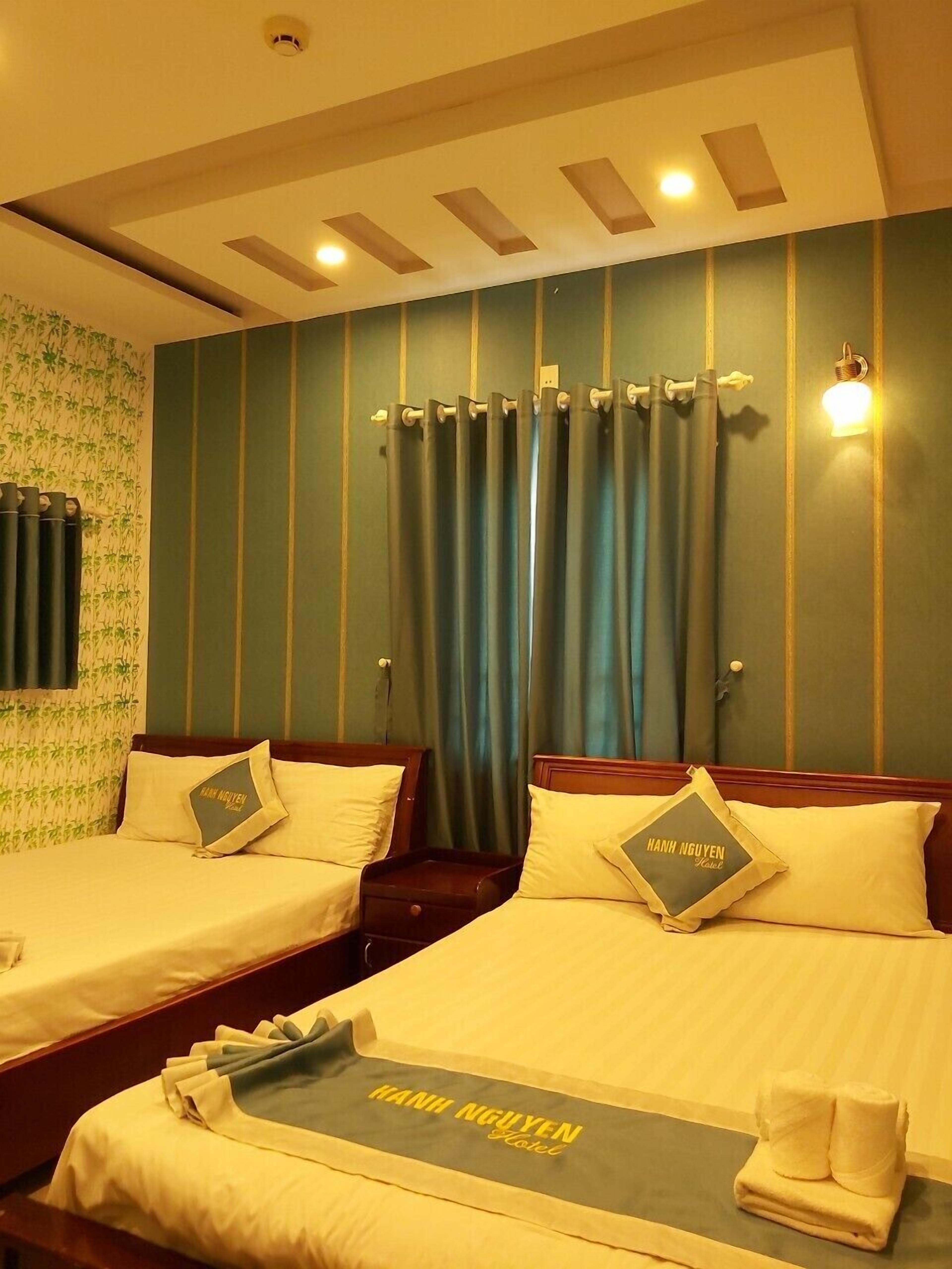 Una habitación de hotel con dos camas, un muro a rayas verdes y una cortinera con cortinas.