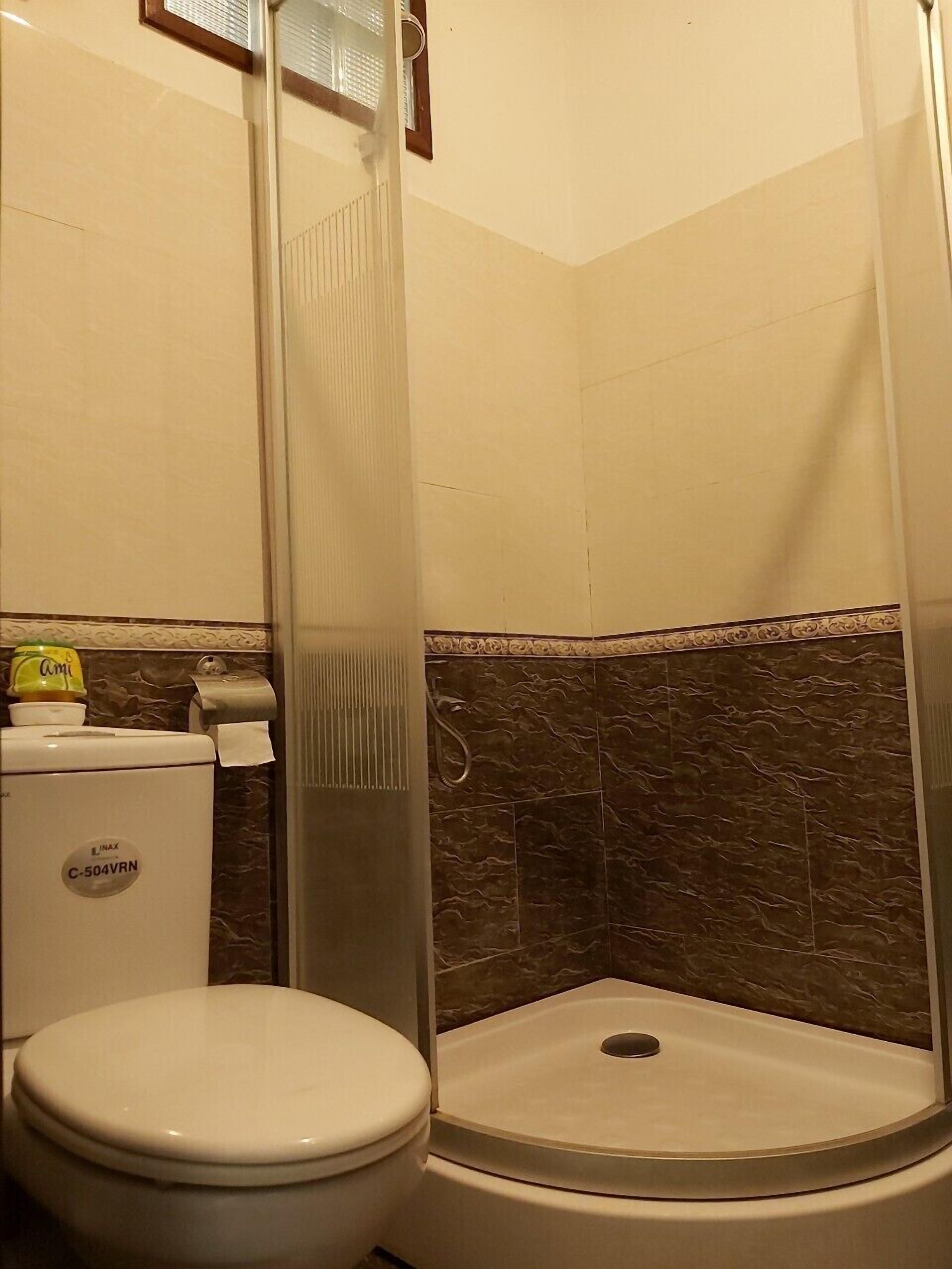 A bathroom with a toilet, a shower stall, and a sink.