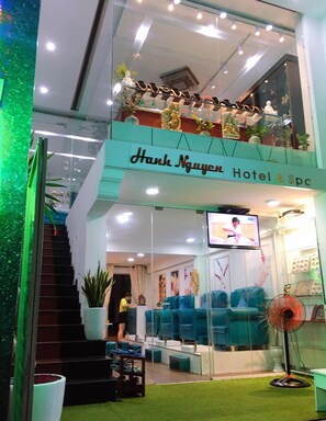 A hotel lobby with a staircase, seating area, and a TV screen.
