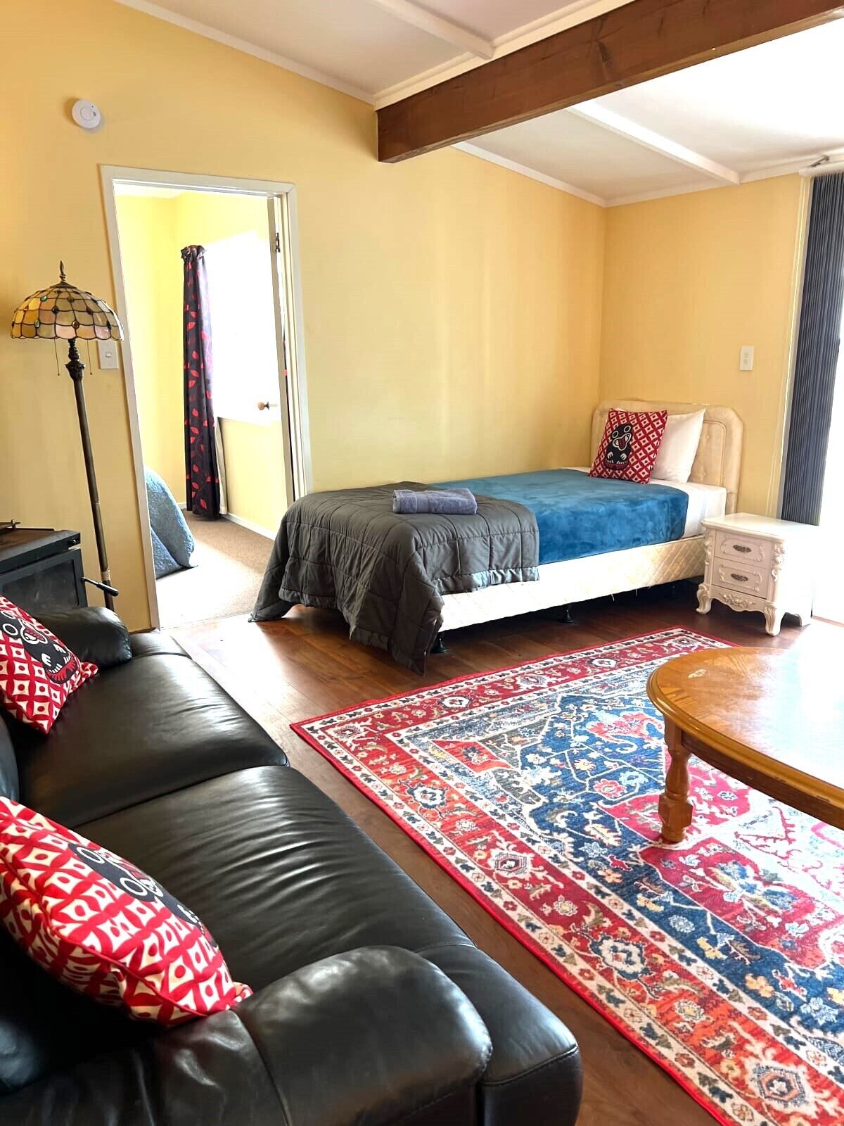 A bedroom with a bed, a nightstand, a dresser, a sofa, and a floor lamp.