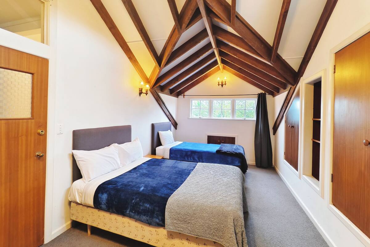 Un dormitorio con dos camas, vigas de madera, una ventana y una puerta.